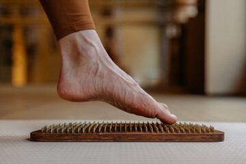 Exploring tactile sensations, a foot interacts with wooden acupressure pegs