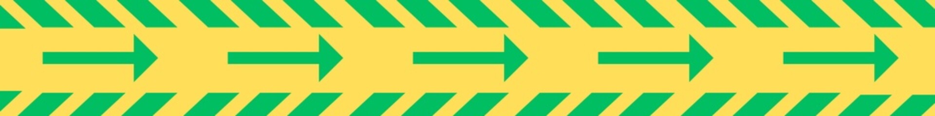 Green arrow and cross diagonal line on yellow tape. Flow and direction adhesive reflective tape. 