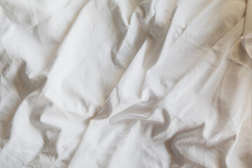 Textured white linen background. Close-up view of a textured white cotton material. The soft folds and creases offer a natural look, perfect for advertising banner background or design elements.