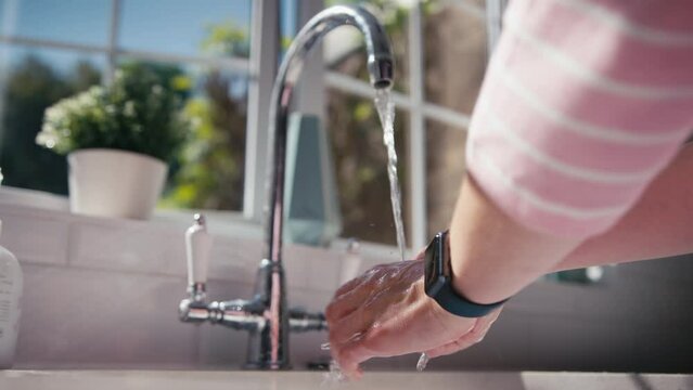 Close up of woman in kitchen washing hands under tap - shot in slow motion