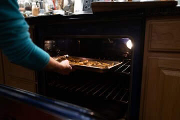 Female hands placing Roasted vegetables on the foil in the oven