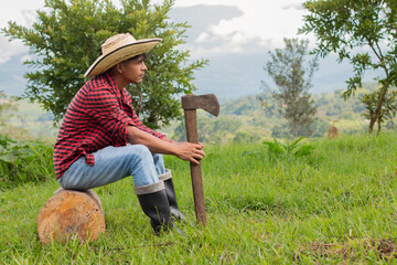 lifestyle: peasant lumberjack sitting on a log with an axe in his hand