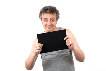 A shaggy gray-haired middle-aged man with stubble in a sleeveless T-shirt holds a black sign...