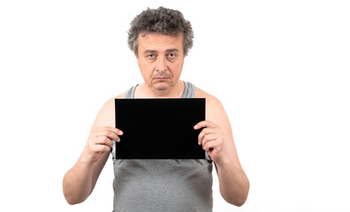 A shaggy gray-haired middle-aged man with stubble in a sleeveless T-shirt holds a black sign...