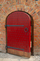 An old wooden door with a red handle in a brick wall.