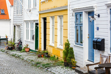 Charming historic old town street in Bergen with traditional white wooden houses and red-tiled roofs along a quaint cobblestone path. Norway