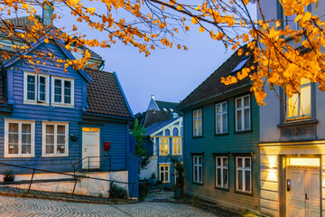 A cozy evening street scene with blue wooden houses in Bergen, Norway.