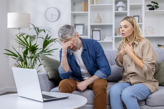 Mature couple appears stressed and anxious while participating in an online consultation with a family psychologist from their living room.