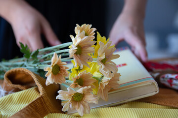 Mujer sostiene un libro en mesa decorada con flores
