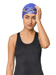 Young Caucasian female professional swimmer tired and very sleepy keeping hand on head.