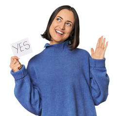 Young Caucasian woman holding "yes" sign in studio