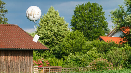 Glückwunschballon mit Brautpaarkarte am Himmel