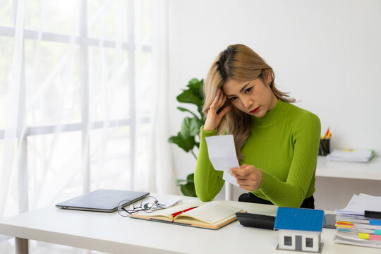 A young Asian woman is worried and frustrated about her monthly expenses. Various utility costs at home include gas and electricity costs. Verify calculations