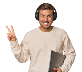 Young student man with a laptop joyful and carefree showing a peace symbol with fingers.