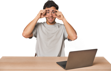Hispanic young man working on laptop keeping eyes opened to find a success opportunity.