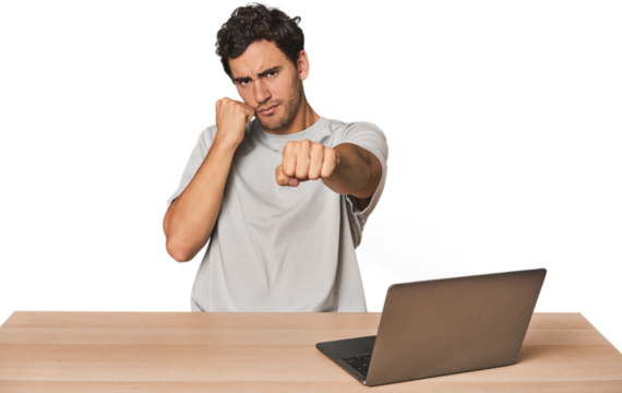 Hispanic young man working on laptop throwing a punch, anger, fighting due to an argument, boxing.