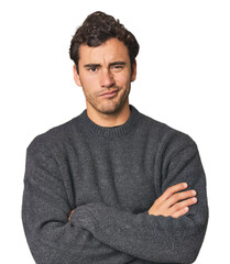 Young Hispanic man in studio frowning face in displeasure, keeps arms folded.