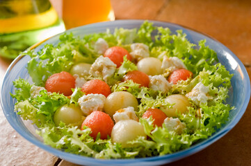 Front view of escarole salad with melon, watermelon and fresh cheese with honey.