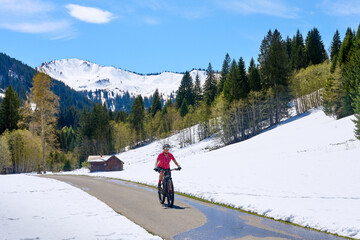 smiling senior woman riding her electric mountain bike on a sunny day in early spring in the...