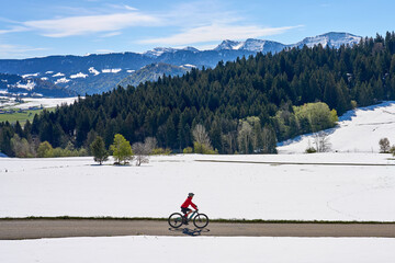 active senior woman riding her electric mountain bike on a sunny day in  spring with Dandelion...