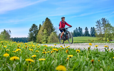 pretty senior woman riding her electric mountain bike in  springtime in the Allgau mountains near...