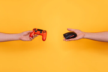 In one hand, a gamepad, and in the other hand, a computer mouse, reaching towards each other...
