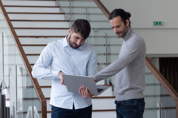 deux jeune hommes d'affaire ou employés de bureau discutent debout dans les locaux de leur...