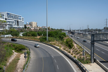 Cars entering the Ayalon highway, in Herzliya, Israel, with clear blue sky.