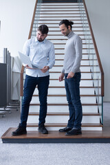 deux jeune hommes d'affaire ou employés de bureau discutent debout dans les locaux de leur...