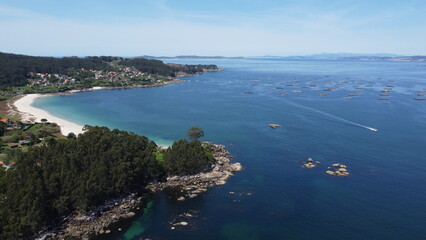 Galicia's coastal beauty captured from above: azure sea, sandy beach, and surrounding trees in aerial view
