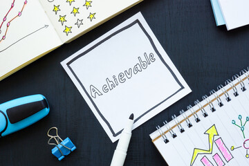 Achievable word and open notebooks with plans and goals.