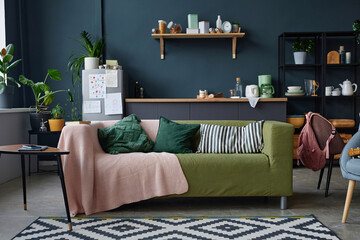 Full length background image of green textile sofa in modern home interior against teal wall with clutter, copy space