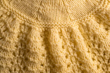 Fragment of hand knitted fabric light yellow. beautiful pattern. full frame.