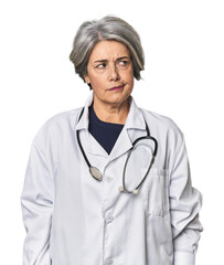 Caucasian mid-age female doctor with stethoscope confused, feels doubtful and unsure.