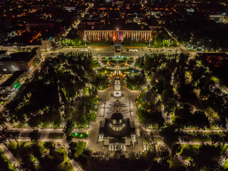 Drone aerial view of a crowd of people at an Easter night service near the cathedral with Chisinau's nightscape in the background, featuring the bell tower, the Triumph Arch, the Government building, 