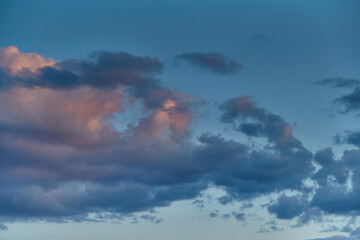 Dark clouds in the blue sky illuminated by the setting sun