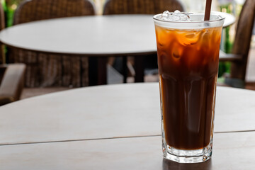 A glass of cold brew iced coffee, cola or cocktail on a cafe table