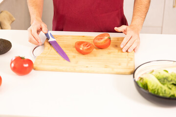 A man is cutting tomatoes on a cutting board