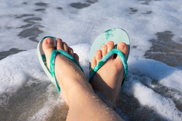 Blue colored summer shoe sandals female woman barefoot on sea shore beach as vacation tourism and...
