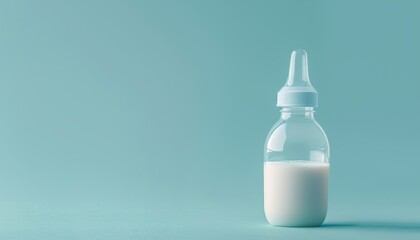 Fototapeta premium Closeup of light blue background and milk filled feeding bottle