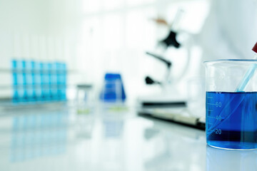 Medical or scientific researcher or man doctor looking at a test tube of clear solution in a laboratory