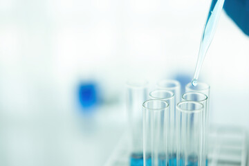 Medical or scientific researcher or man doctor looking at a test tube of clear solution in a laboratory