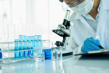 Medical or scientific researcher or man doctor looking at a test tube of clear solution in a...