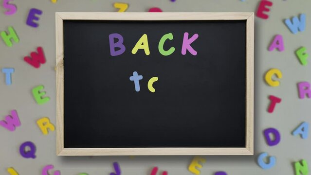 Back to School Stop motion. Chalk inscription appears on blackboard on background of multi-colored letters. Concept of beginning of school year. First day of preschool. Welcome text.