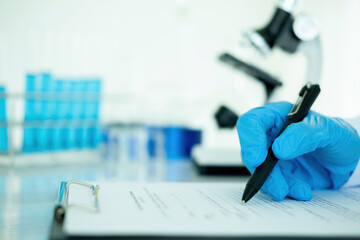 Medical or scientific researcher or man doctor looking at a test tube of clear solution in a...