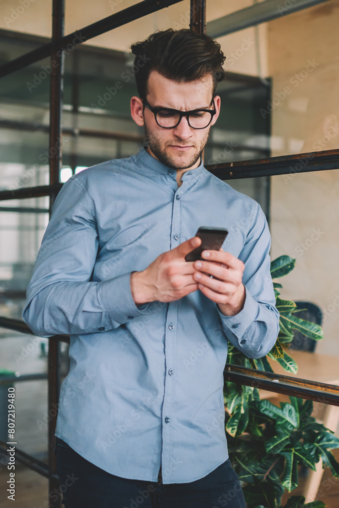 Poster perplexed caucasian man reading sms message via smartphone device browsing internet indoors, confuse