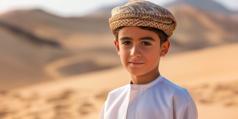 A portrait of a young boy donning traditional headwear against the backdrop of a desert landscape