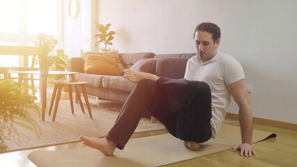Young male doing mobility routine at home with foam rolling massage