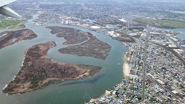 The plane's descent offers  view of coastline and the serene suburban landscape below as it approaches a New York airport.