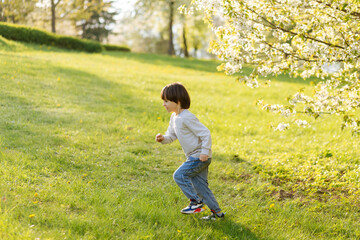 happy little cute boy running on children playground, green nature sunny background, happy freedom childhood.